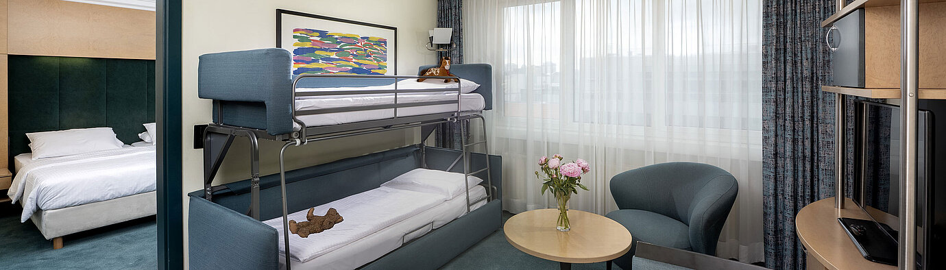 Family suite with bunk bed, sofa, table and view into bedroom at Maritim proArte Hotel Berlin