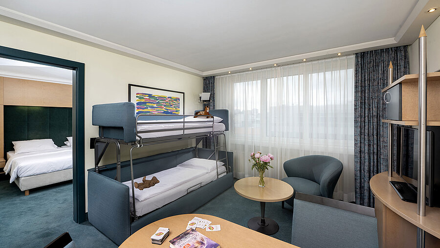 Family suite with bunk bed, sofa, table and view into bedroom at Maritim proArte Hotel Berlin