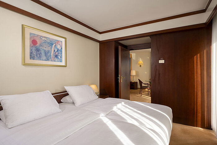 Bright bedroom with double bed and artwork on the wall in the Senior Suite at Maritim Hotel Köln