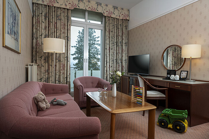 Family-friendly seating area with toys, sofa, TV and balcony at Maritim Hotel Bad Wildungen