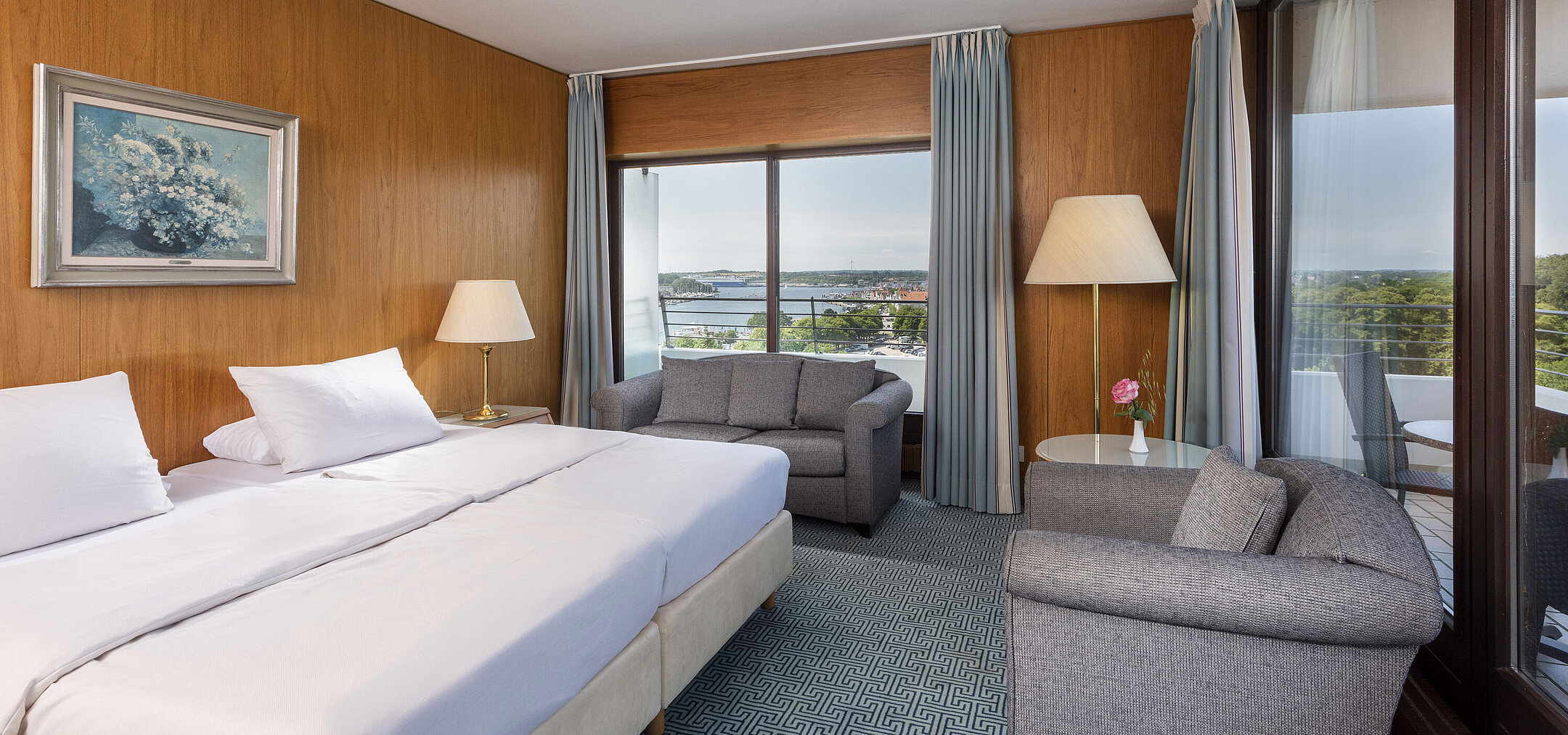 Modern double room with cosy seating area and large window overlooking Lübeck Bay