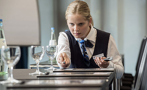 Service staff preparing conference room at Maritim Hotel Bad Homburg with glasses and stationery.