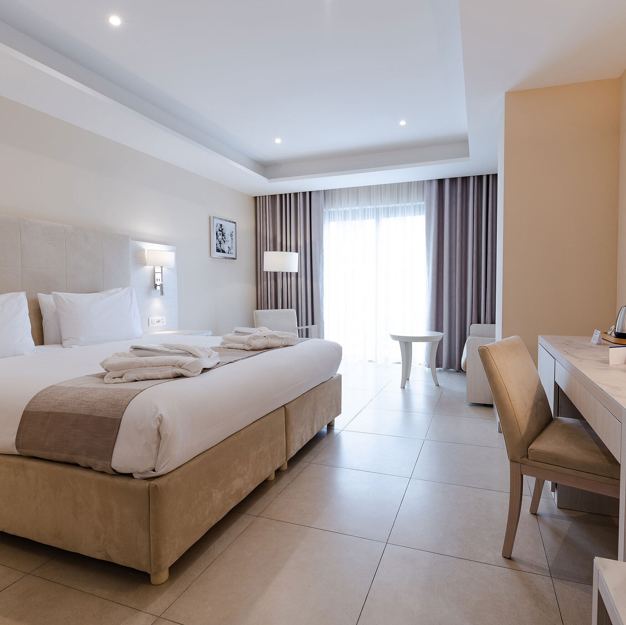 Spacious double room with desk, seating area, TV and floor-to-ceiling window