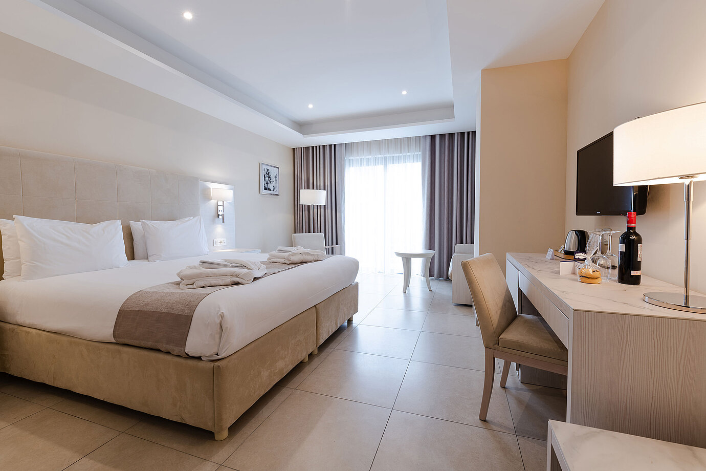 Spacious double room with desk, seating area, TV and floor-to-ceiling window