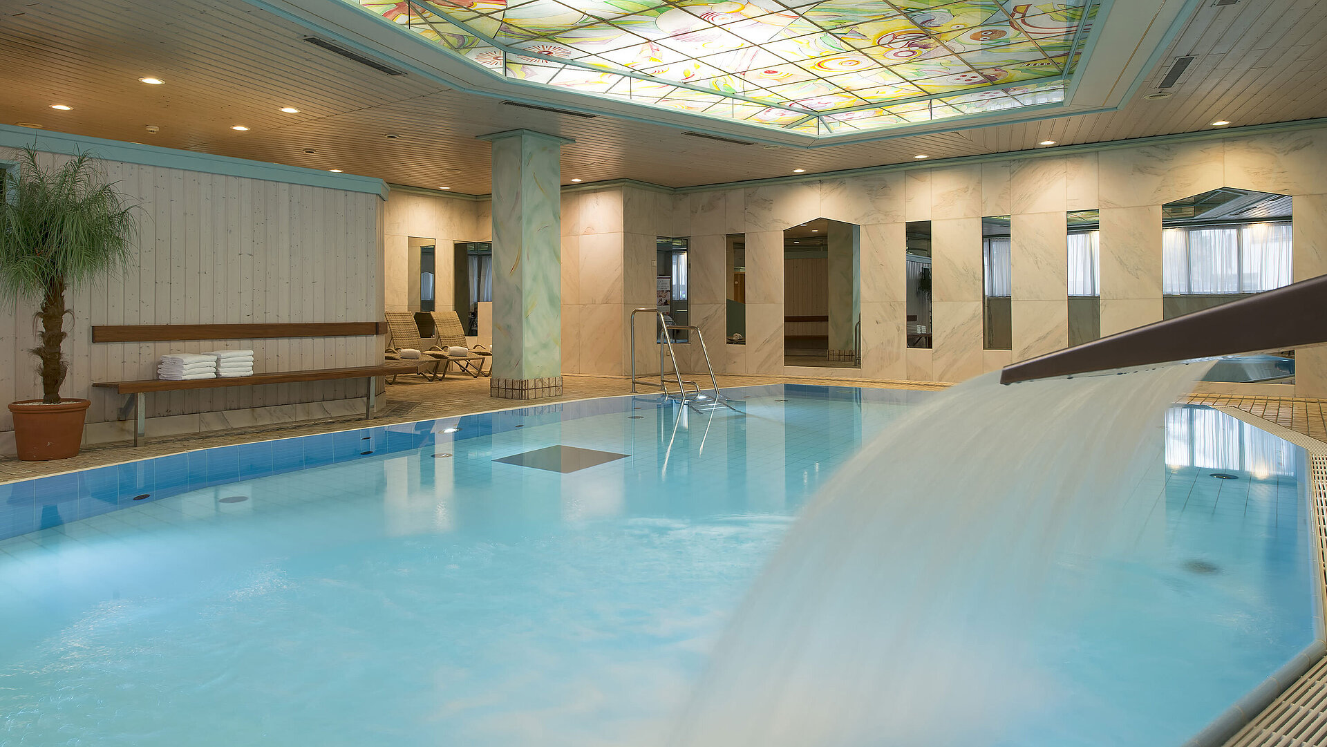 Heated indoor pool with waterfall and colourful glass ceiling at the Maritim Hotel Stuttgart