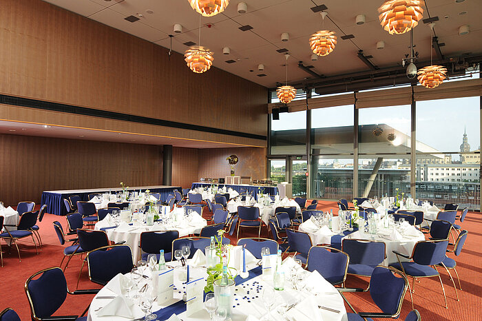 Elegant event hall in Maritim Hotel Dresden with festively set tables and a view of the city.