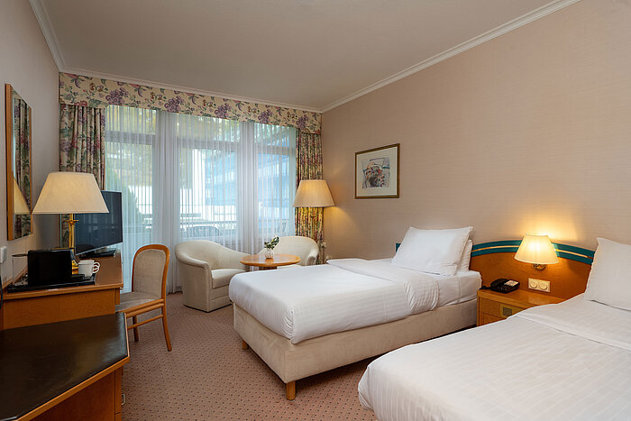 Comfort Twin room with two single beds, desk, seating area and large window for plenty of daylight.