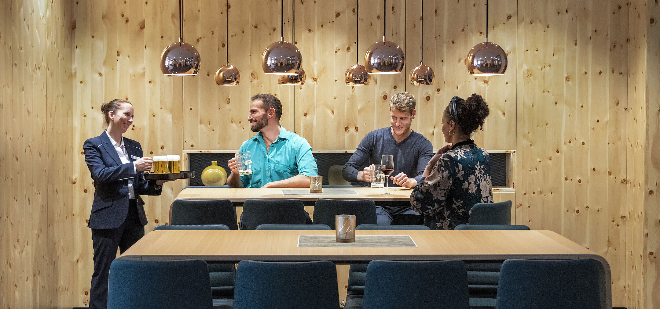 Guests enjoying drinks in a cozy atmosphere while a friendly staff member serves.