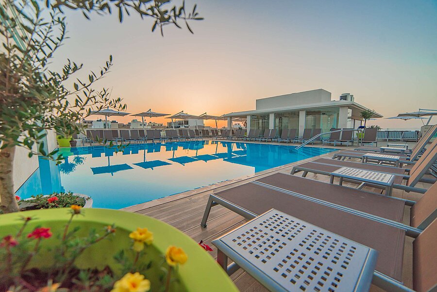Outdoor pool with sun loungers and parasols during atmospheric sunset