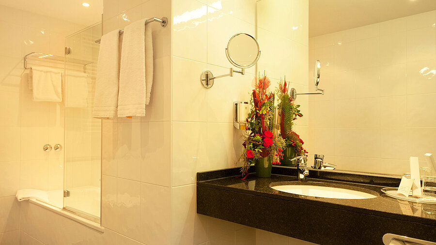Modern bathroom with shower, towels and washbasin at Hansa Hotel Wiesbaden