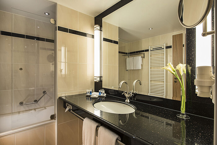 Modern bathroom with sink, mirror, bathtub, and elegant details at Maritim Hotel Dresden.
