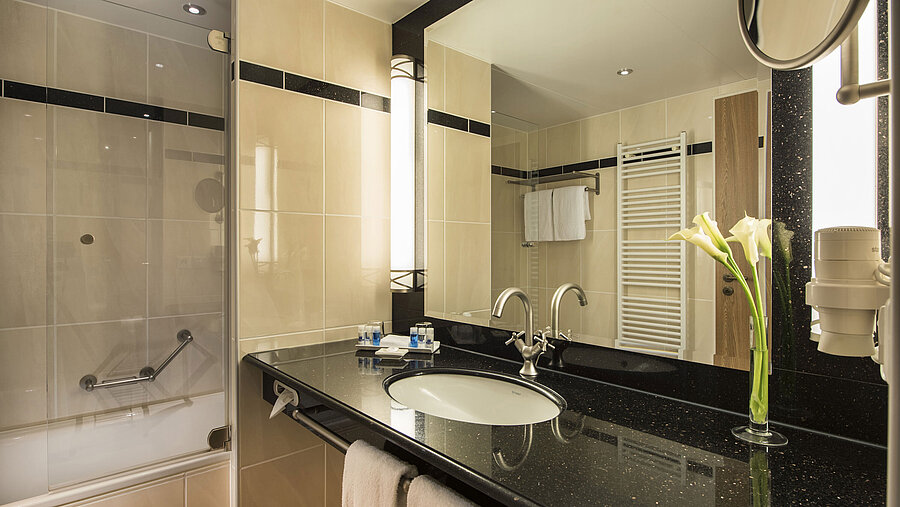 Modern bathroom with sink, mirror, bathtub, and elegant details at Maritim Hotel Dresden.