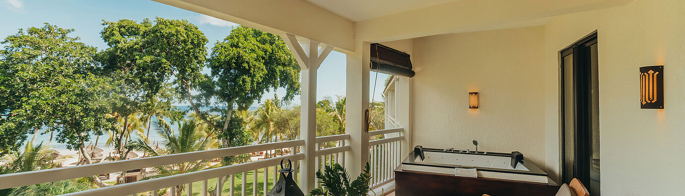 Terrace of the Penthouse Suite with seating, sun loungers and views of tropical greenery and the sea.