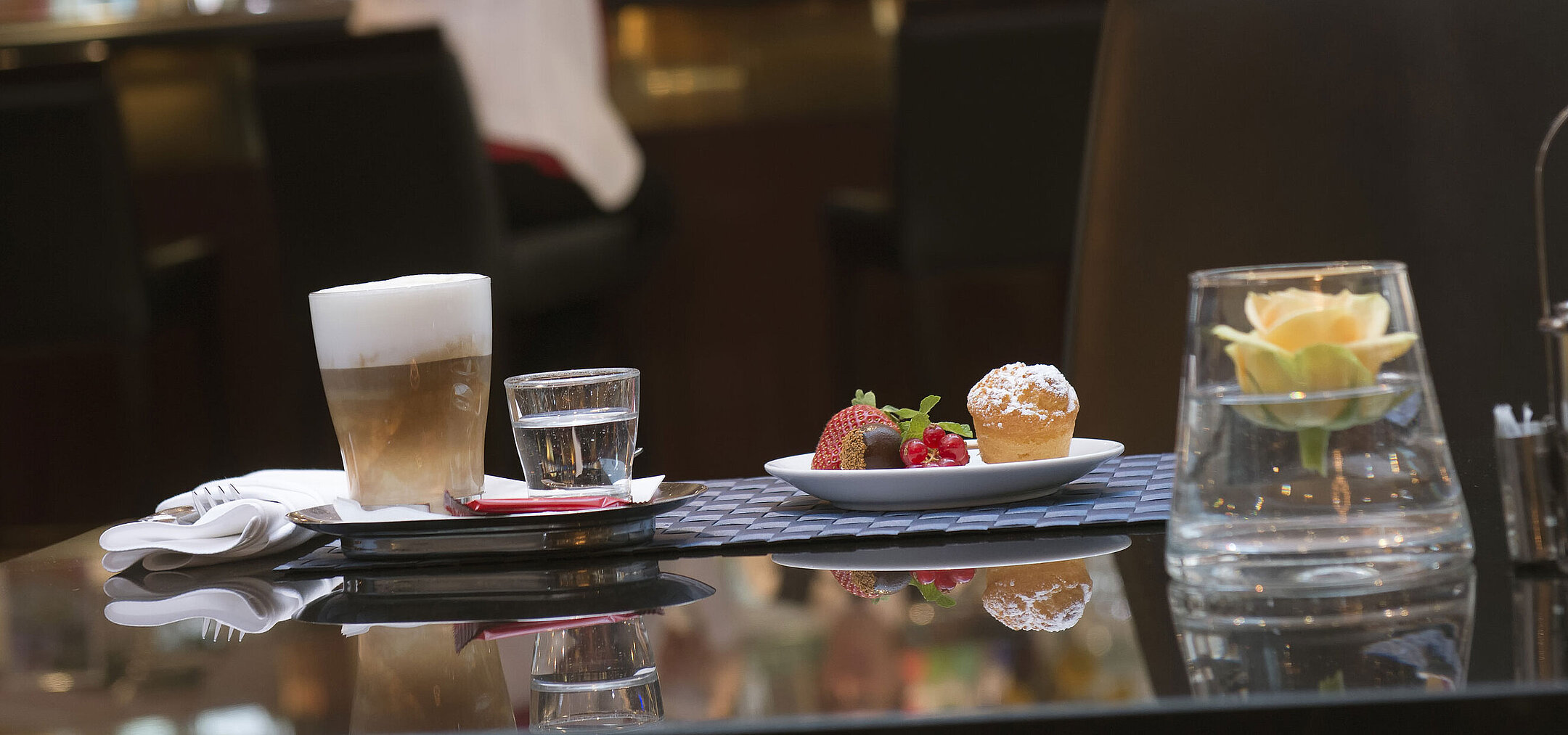 Latte macchiato and pastry at the café in Maritim Hotel Stuttgart with bar view in the background