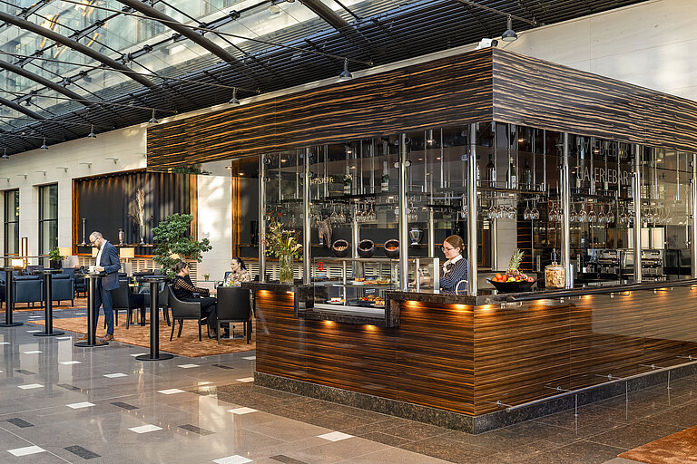 Modern Galerie Bar at Maritim Hotel Düsseldorf with elegant design, cozy seating areas, and a staff member behind the counter