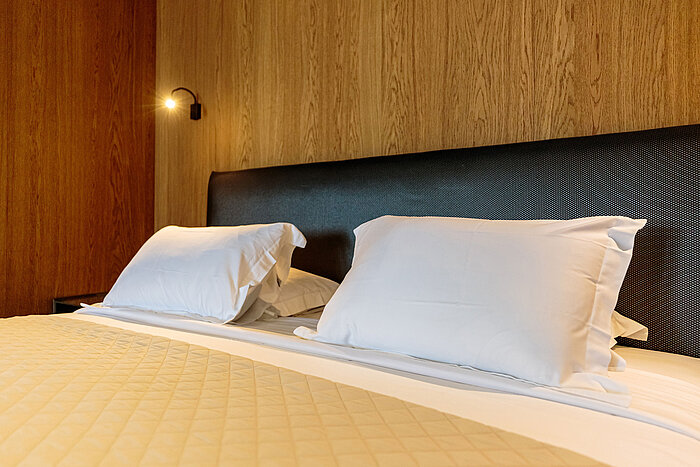Comfortable bed at Maritim Resort Marina Bay with wood design and soft lighting