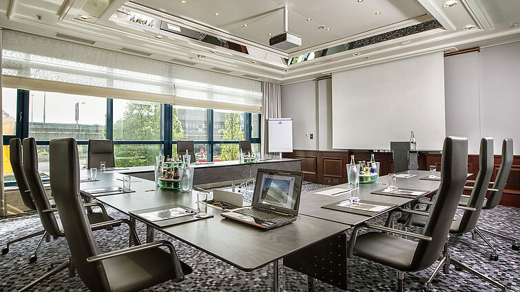 Bright meeting room with a large conference table, leather chairs, and modern technology.
