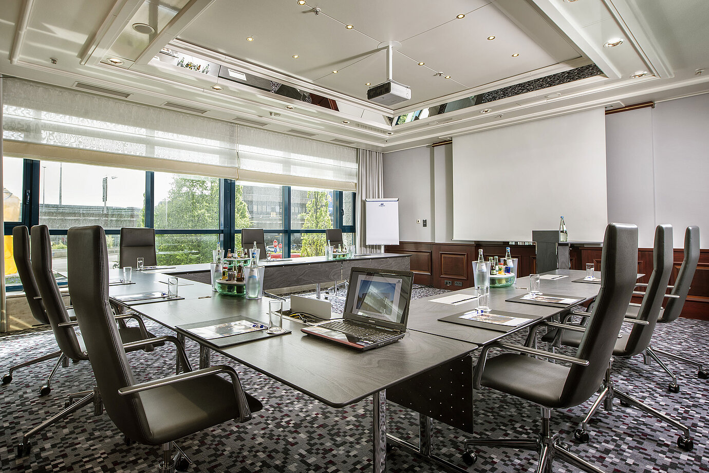 Bright meeting room with a large conference table, leather chairs, and modern technology.