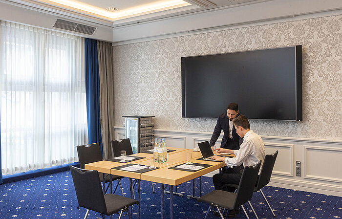Two people working in the Salon Oegg at the Maritim Hotel Würzburg with a modern screen.