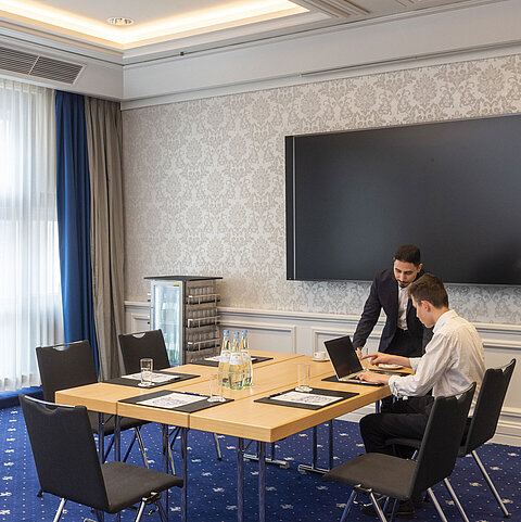 Two people working in the Salon Oegg at the Maritim Hotel Würzburg with a modern screen.