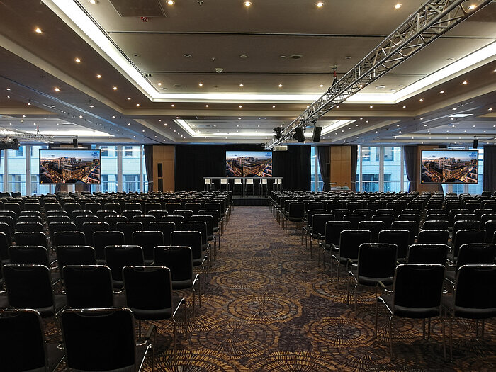Large conference room with modern equipment and row seating at the Maritim proArte Hotel, ideal for conferences and events.