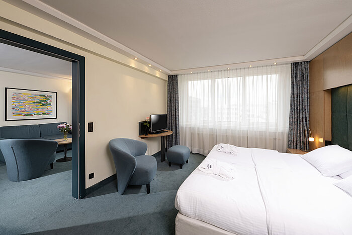 Suite bedroom with double bed and view into the living room at Maritim proArte Hotel Berlin