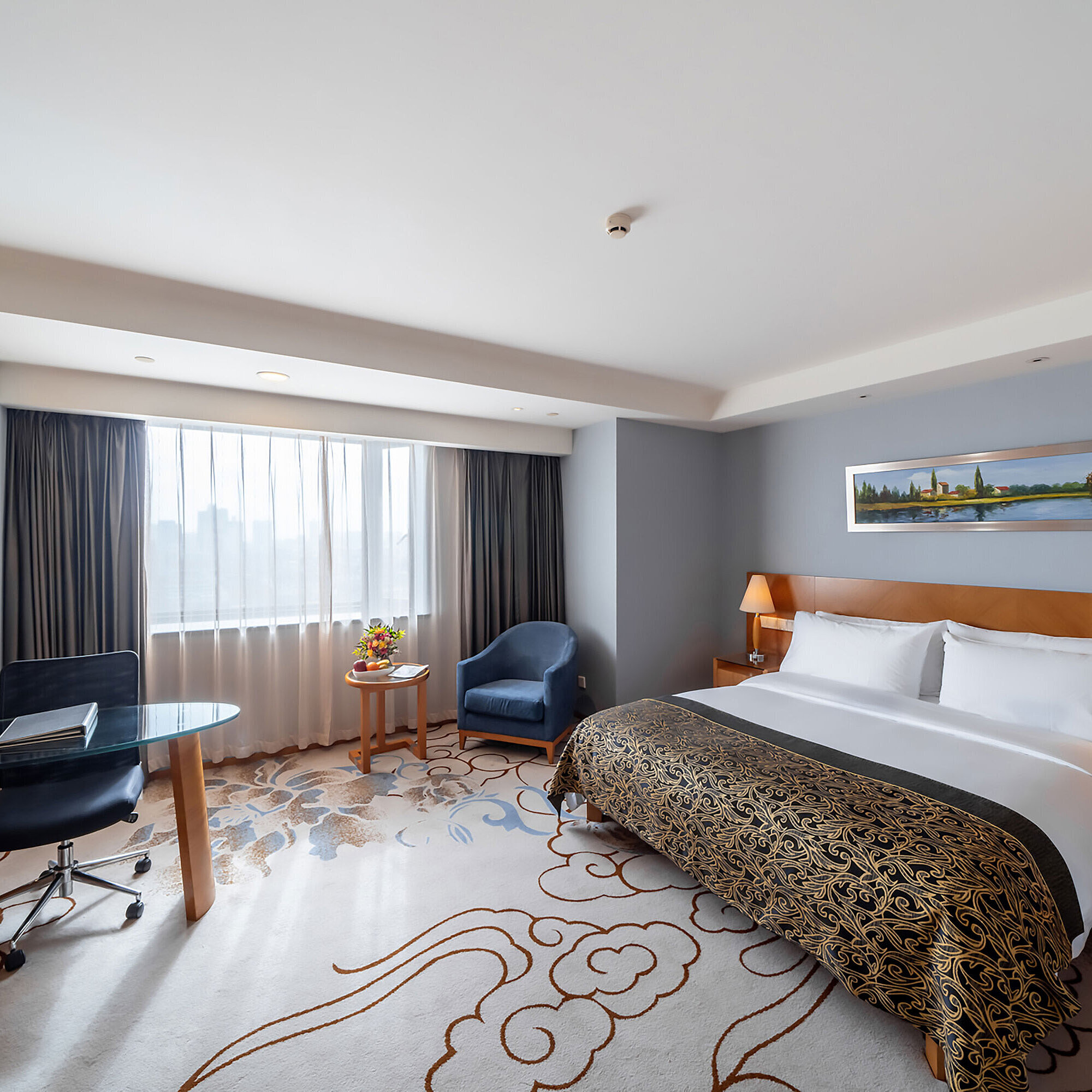 寬敞的酒店客房配備特大床、現代化工作區、藍色扶手椅及大面積落地窗，採光充足