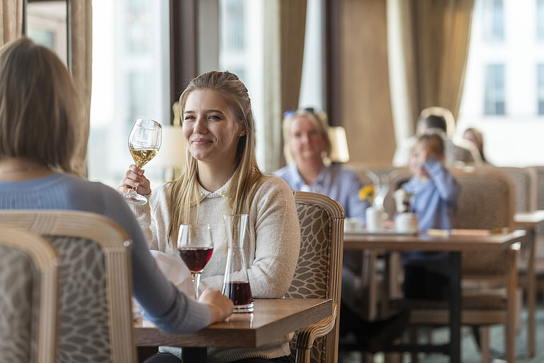 Woman with white wine enjoying the elegant restaurant atmosphere at Maritim Hotel Travemünde