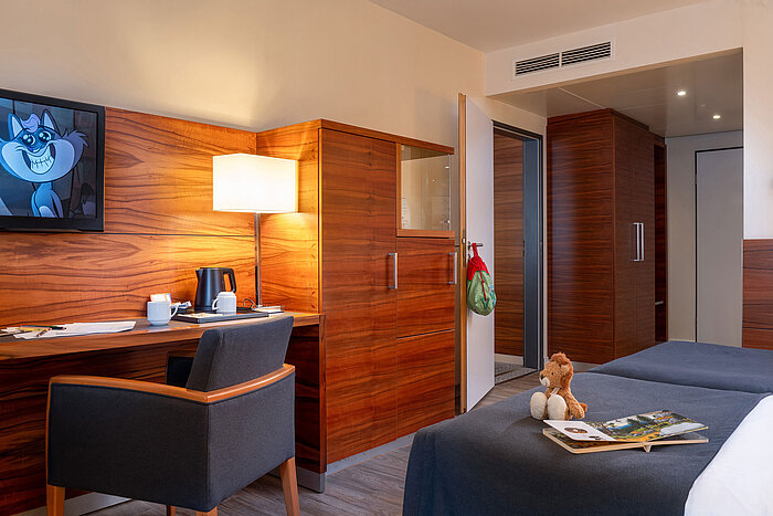 Family room with wooden furniture, desk and TV at the Maritim Hotel München.