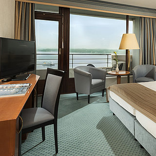 Superior room at the Maritim Hotel Kiel with desk, seating area, large double bed and balcony overlooking the fjord.