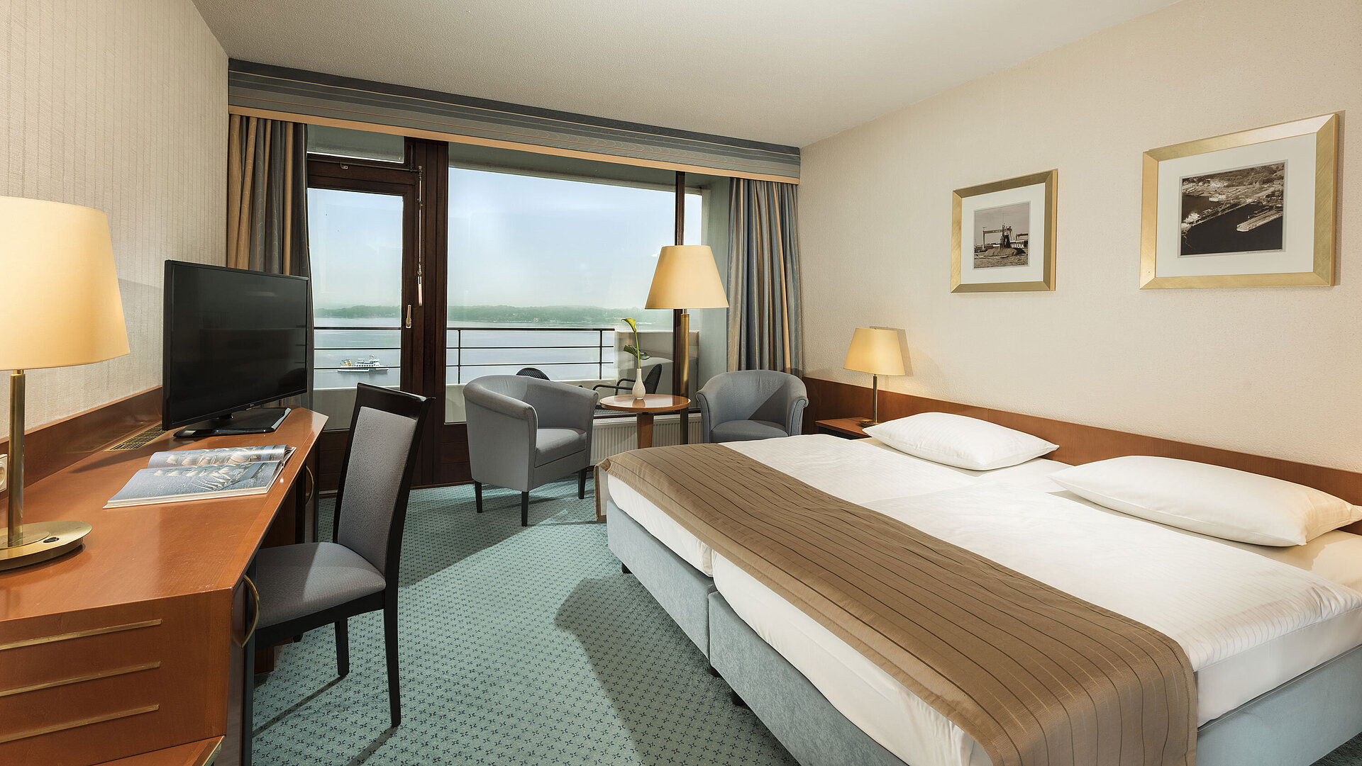 Superior room at the Maritim Hotel Kiel with desk, seating area, large double bed and balcony overlooking the fjord.