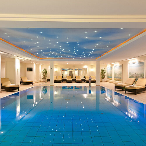 Luxurious indoor pool at the Maritim Hotel Dresden with loungers and atmospheric ceiling lighting.