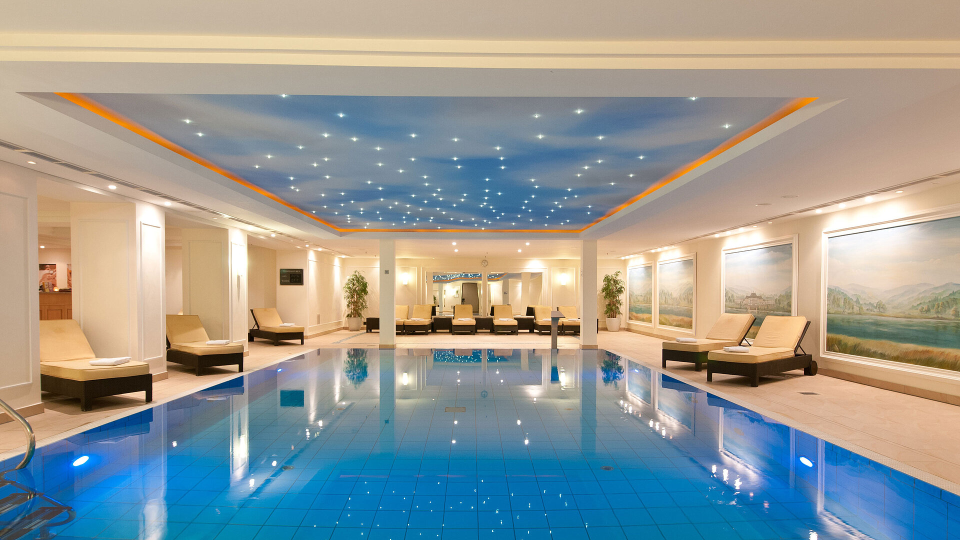 Luxurious indoor pool at the Maritim Hotel Dresden with loungers and atmospheric ceiling lighting.