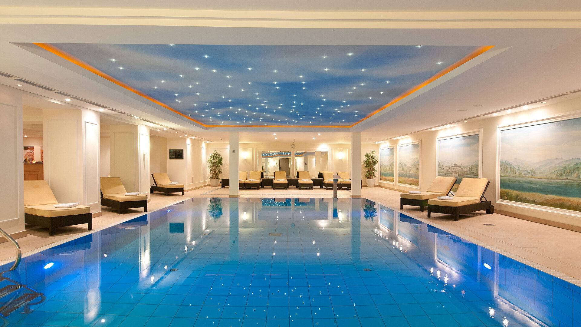 Luxurious indoor pool at the Maritim Hotel Dresden with loungers and atmospheric ceiling lighting.
