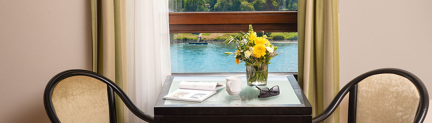 Table and seating by the window in the Junior Suite at Maritim Hotel Königswinter overlooking the River Rhine.