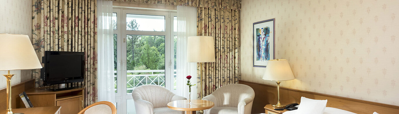 Bright double room with balcony view and seating area at Maritim Hotel Bad Wildungen