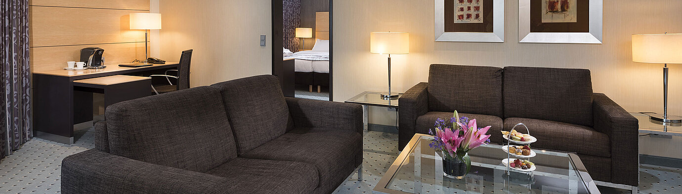 Junior Suite at Maritim Hotel Düsseldorf with separate living area, two sofas, desk, flowers, and modern design.