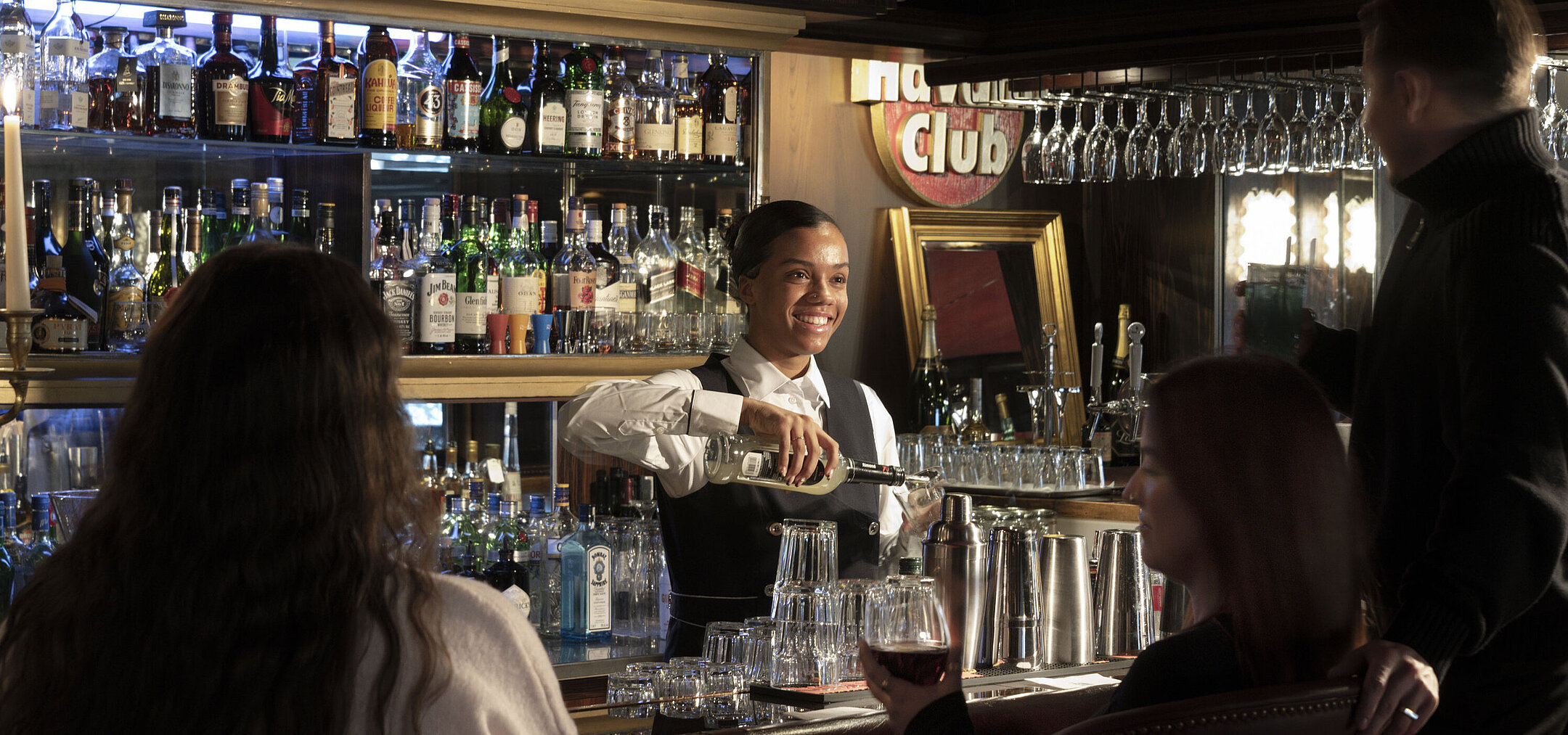 Bartender at the stylish bar in Maritim Hotel Kiel serving drinks with a friendly smile and inviting atmosphere.