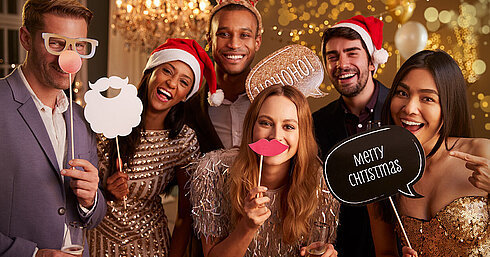 © Monkey Business - AdobeStock.com Elegant group celebrating Christmas party with sparkling wine and Santa hats in golden setting