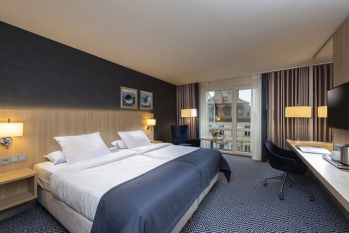 Elegant Superior Room at Maritim Hotel Würzburg with a large double bed and view of historic rooftops