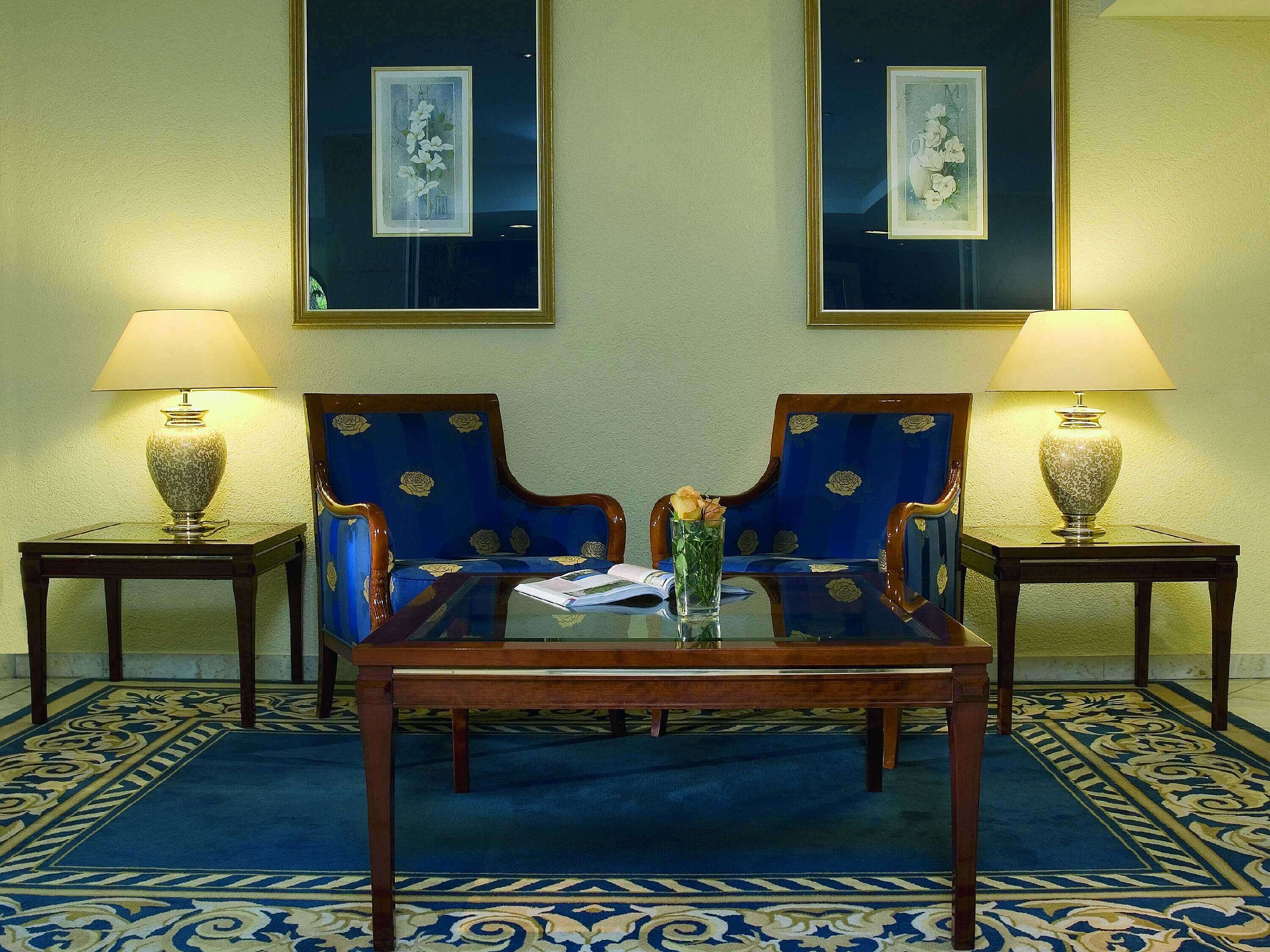 Elegant lobby at Maritim Hotel Fulda with blue armchairs, glass table, and stylish lighting.