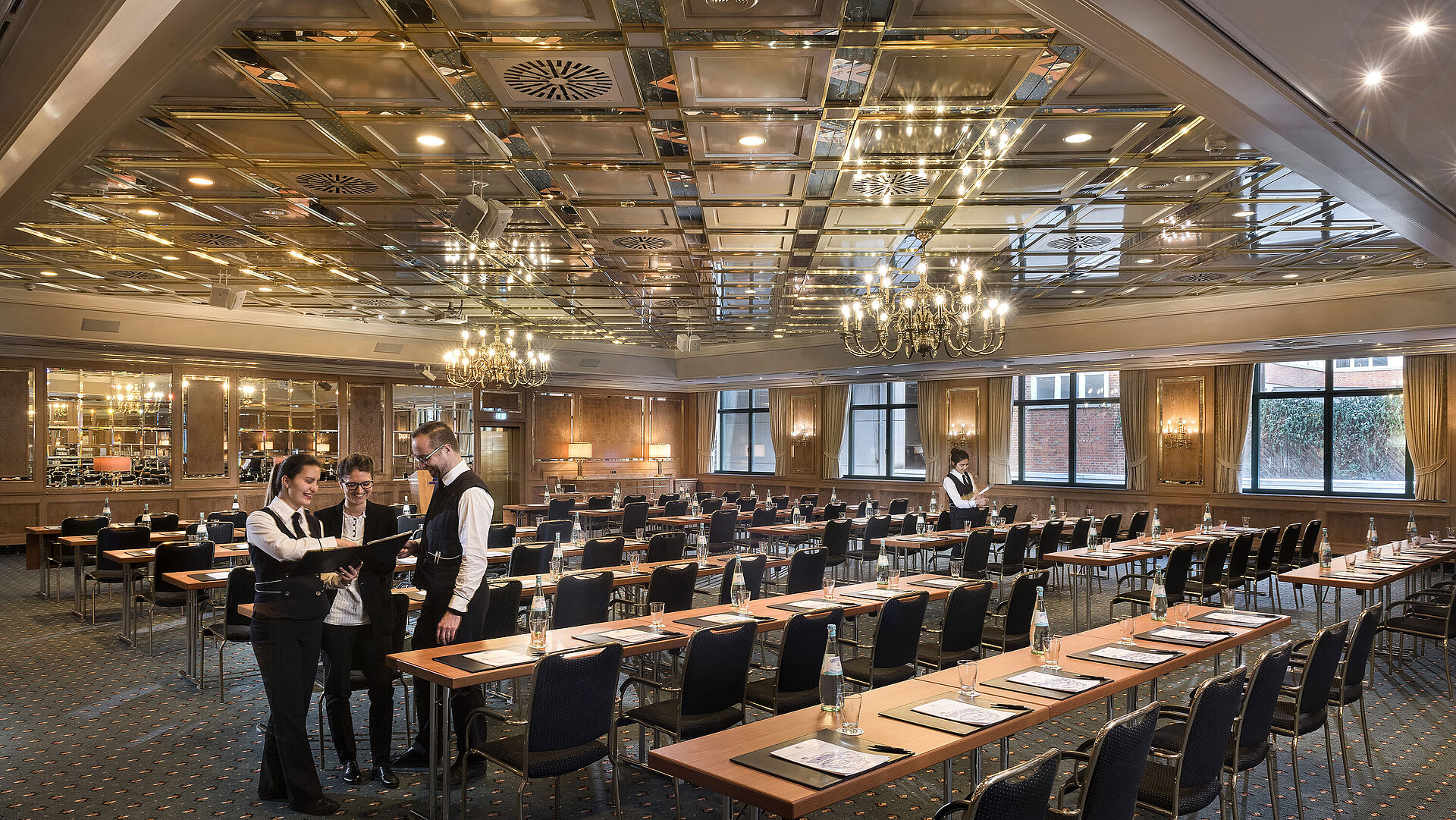 Two staff members preparing a conference room with row seating at Maritim Hotel Stuttgart