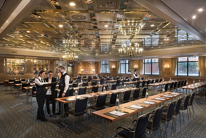 Two staff members preparing a conference room with row seating at Maritim Hotel Stuttgart