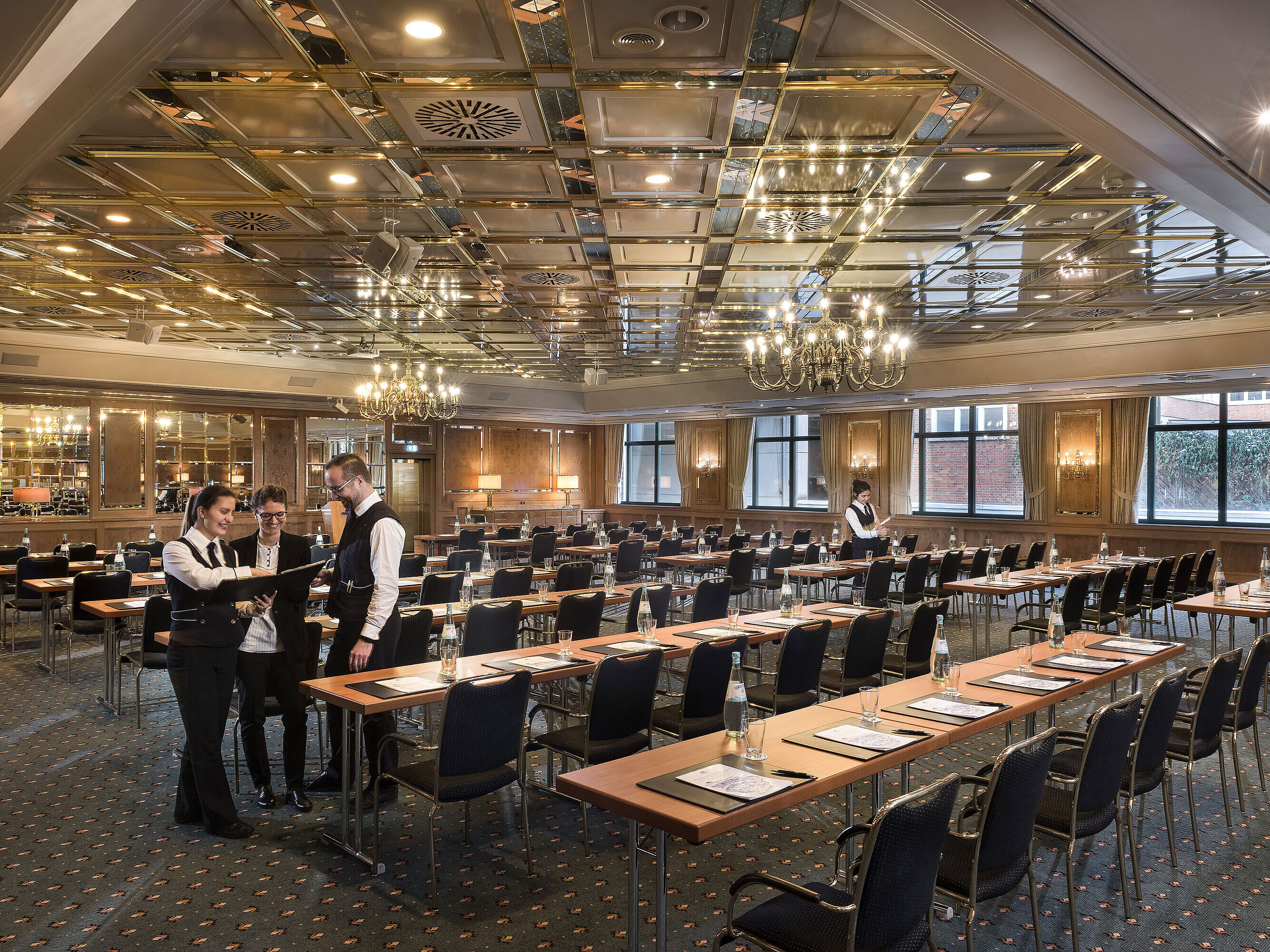 Two staff members preparing a conference room with row seating at Maritim Hotel Stuttgart