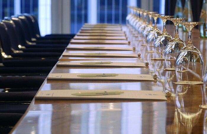 Close-up of a prepared conference table at Maritim proArte Hotel Berlin, with notebooks and wine glasses.