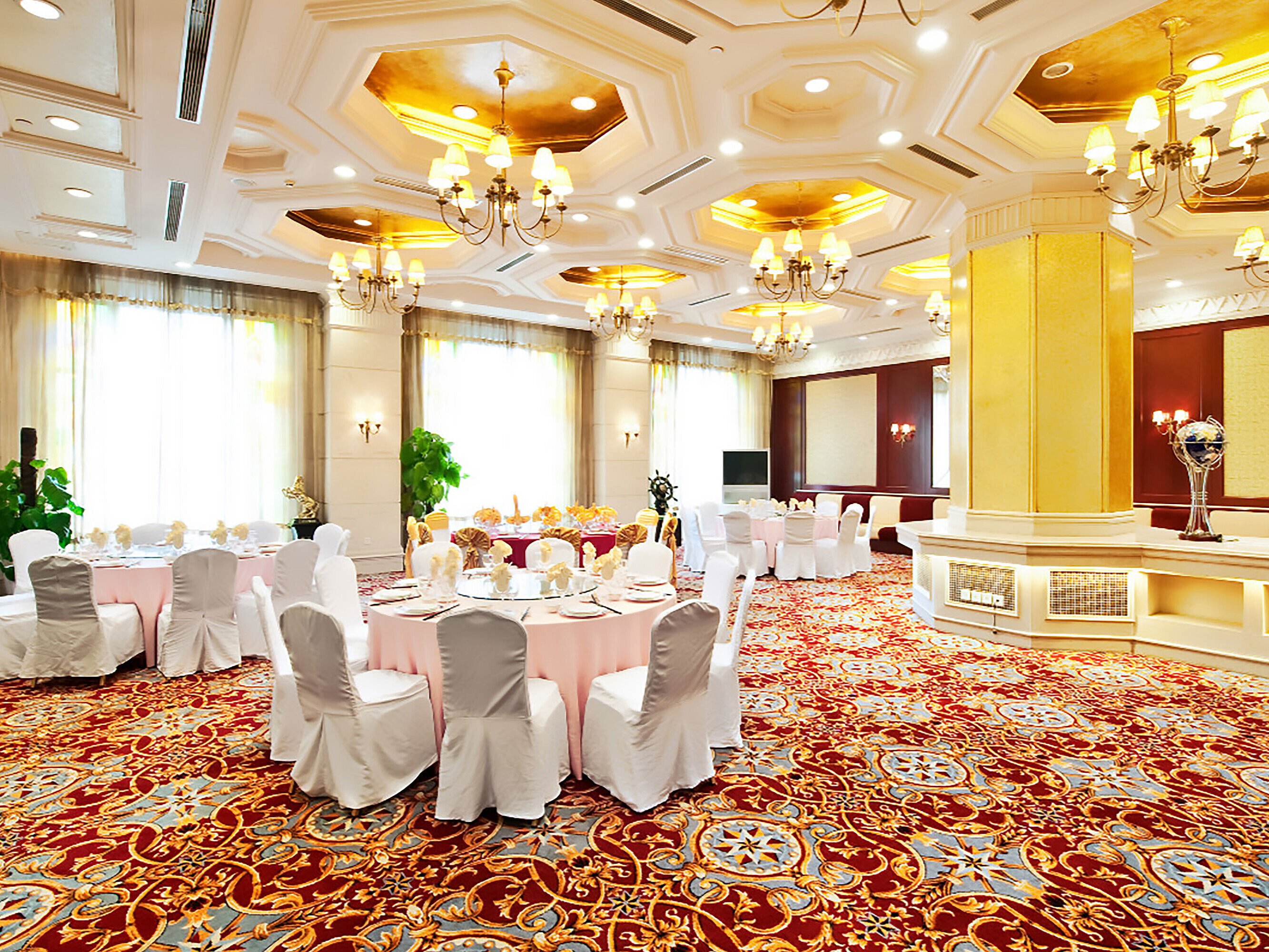 優雅的宴會廳配有金色天花板細節、圓形餐桌、白色椅套及歡慶氛圍