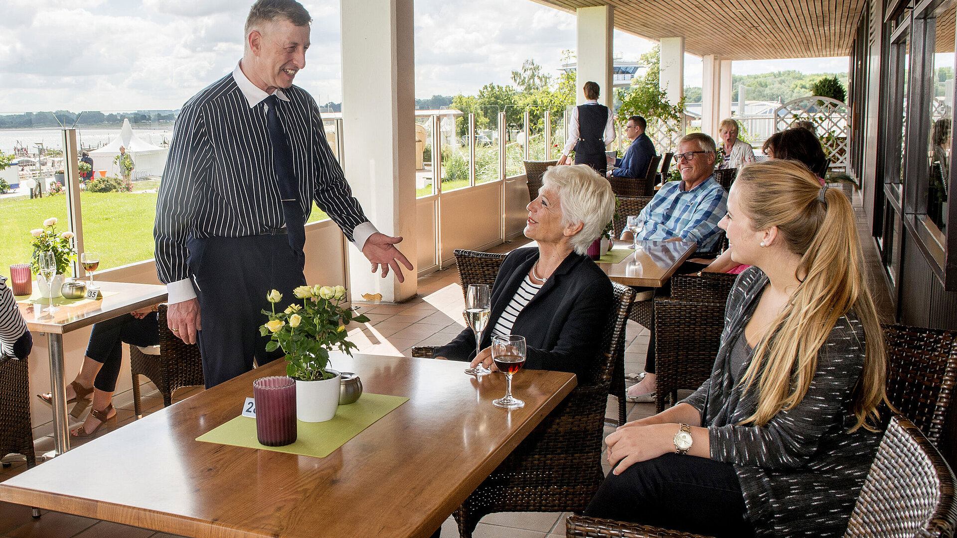 Guests enjoy drinks and conversation on the terrace of Maritim Hotel Travemünde with Baltic Sea view.