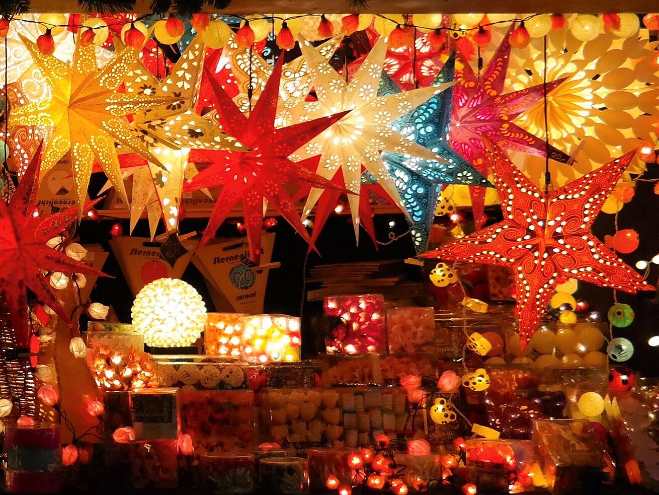 Colourful illuminated paper stars and festive lights displayed at a Christmas market stall