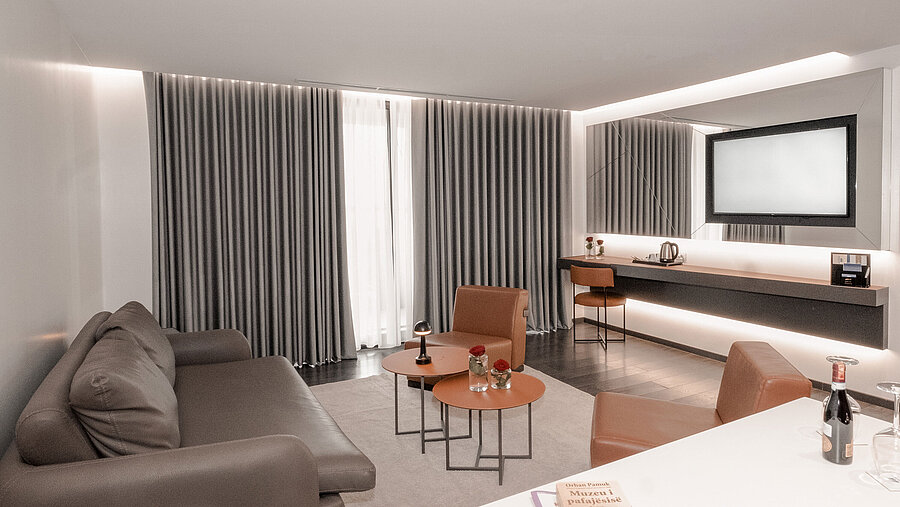 Modern living room at Maritim Resort Marina Bay with sofa, chairs, curtains and elegant lighting