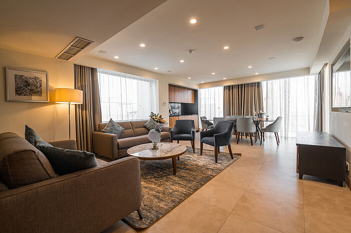 Spacious living and dining area with sofa, armchairs, dining table and floor-to-ceiling windows